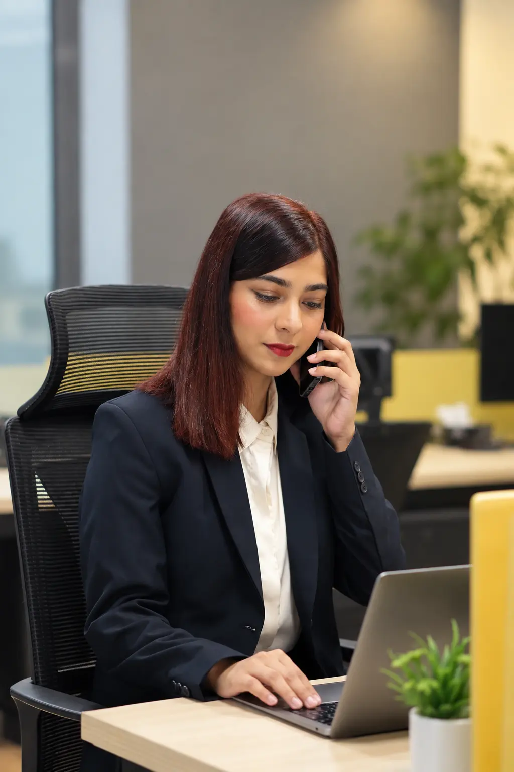 An accountant at a desk taking a phone call while working on a laptop.