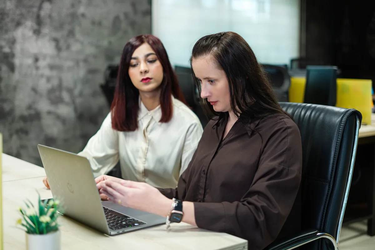 Two team members working through figures together on a laptop