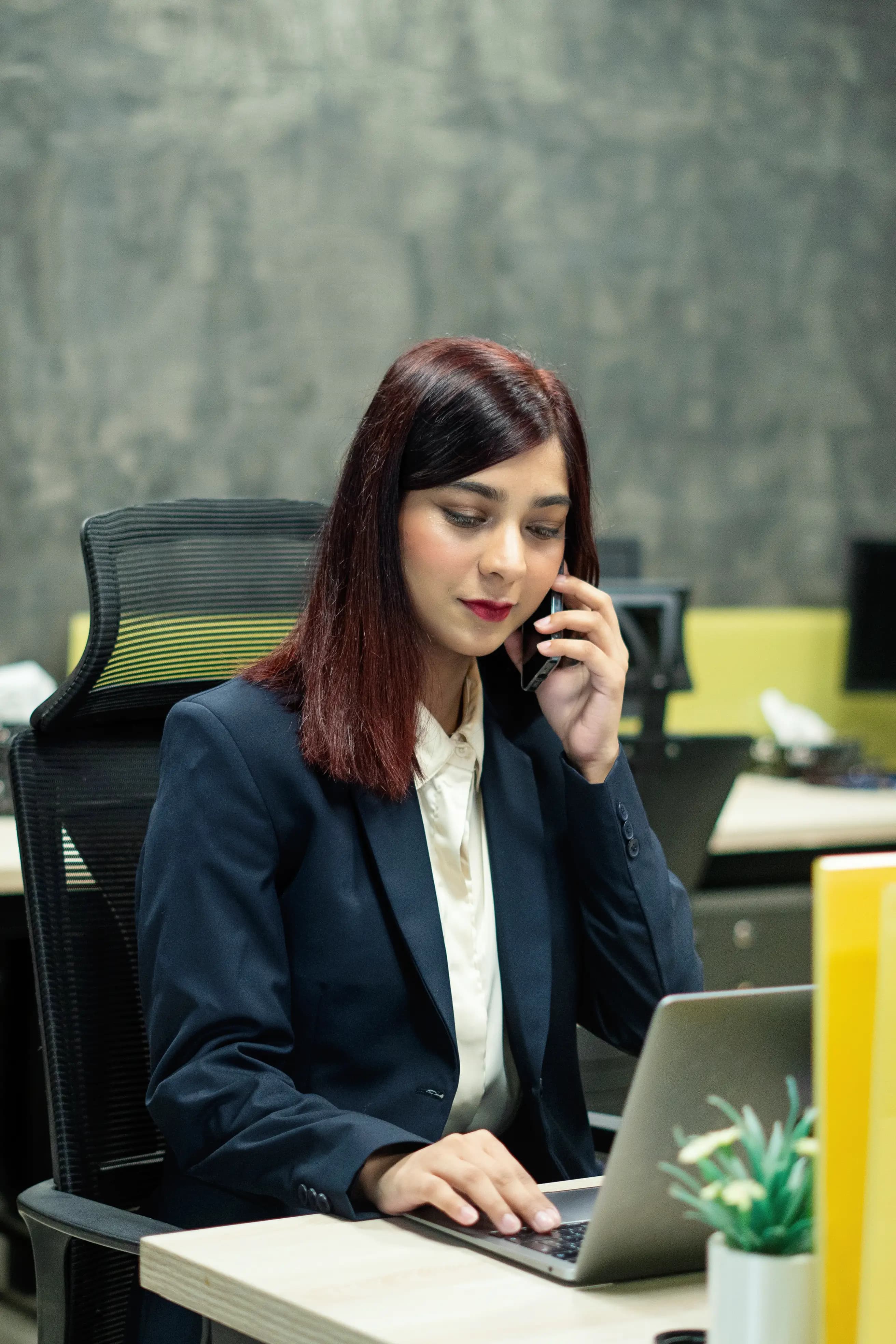 An accountant at a desk taking a phone call while working on a laptop.